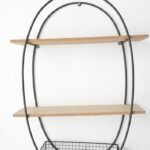 Black oval metal wall shelf with two wooden platforms and a wire storage basket at the base, Lagos, Nigeria