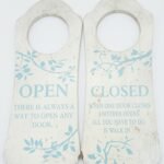 White vintage-style wooden door hanger with blue floral details and inspirational Open/Closed text in Lagos, Nigeria