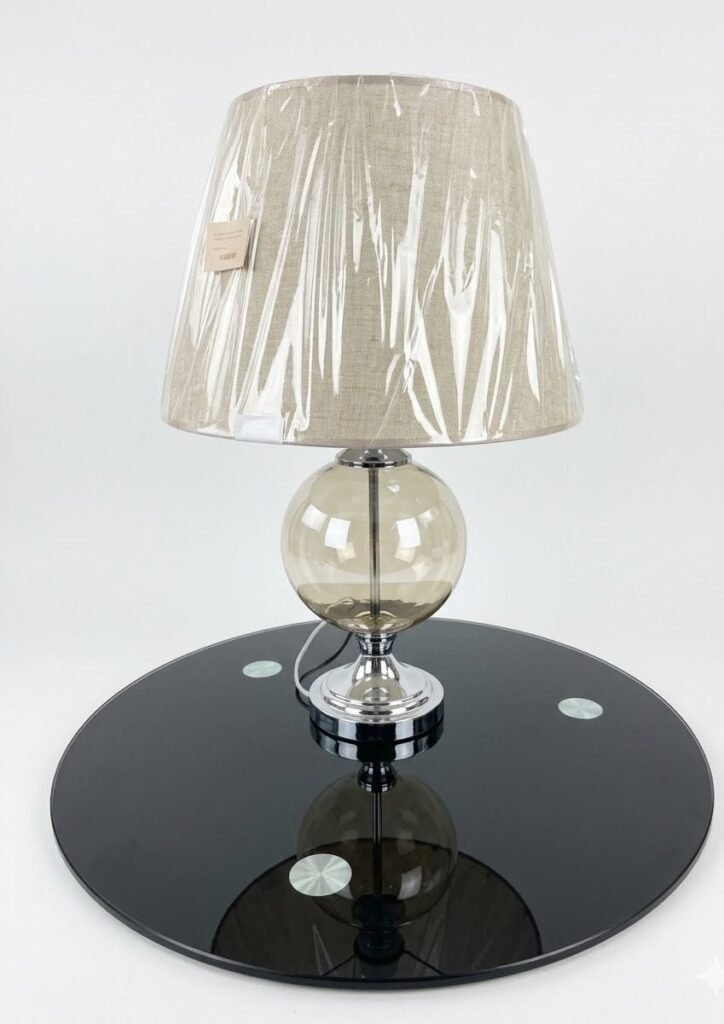 Modern side table lamp with a gold funnel shade and clear glass base for luxury decor in Lagos, Nigeria.