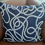 Navy blue outdoor cushion with white marine rope knot pattern, packaged in a clear plastic bag for delivery, Lagos