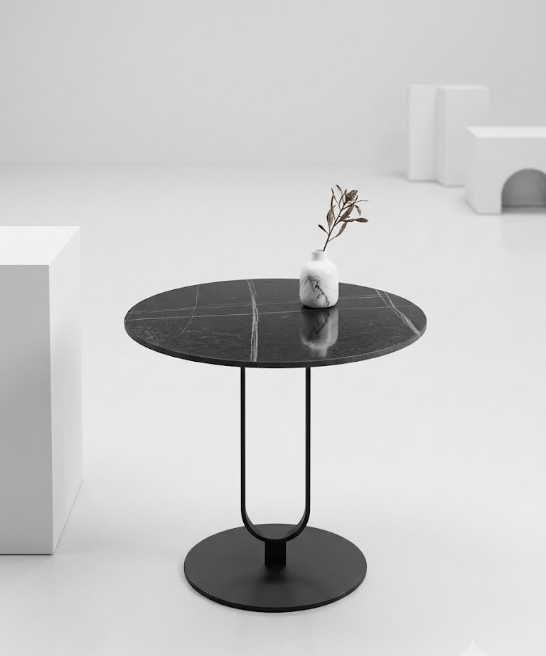 Modern round black sintered stone side table with white marble veining and metal pedestal base in Lagos, Nigeria.