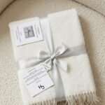 Folded white terry cotton blanket with fringe edges and a silver ribbon bow, Lagos, Nigeria