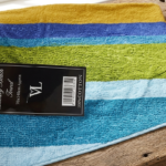 Blue, green, and yellow striped velour cotton beach towel with luxury brand tag in Lagos, Nigeria