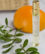 Crushed Black Pepper & Sweet Orange EDP with a gold cap next to an orange.