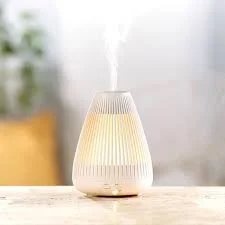 Stylish aroma diffuser releasing mist with soft ambient lighting in a modern home setting
